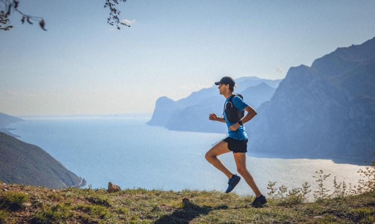 Corridore su sentiero montano con vista lago.