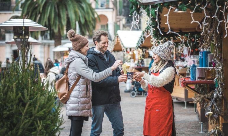 Menschen auf dem Weihnachtsmarkt, teilen Essen und heiße Getränke.