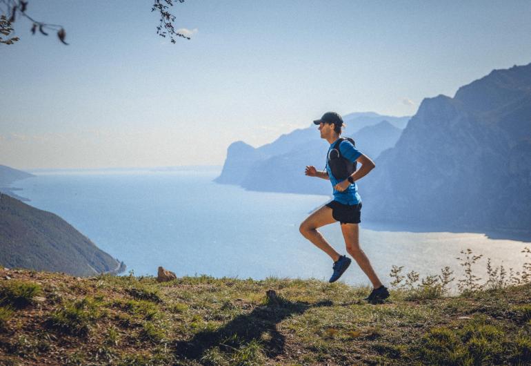 Runner on mountain trail with lake view.